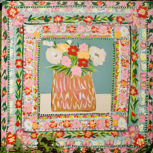 Floral quilt with a vase of flowers in the center, set against a natural background.