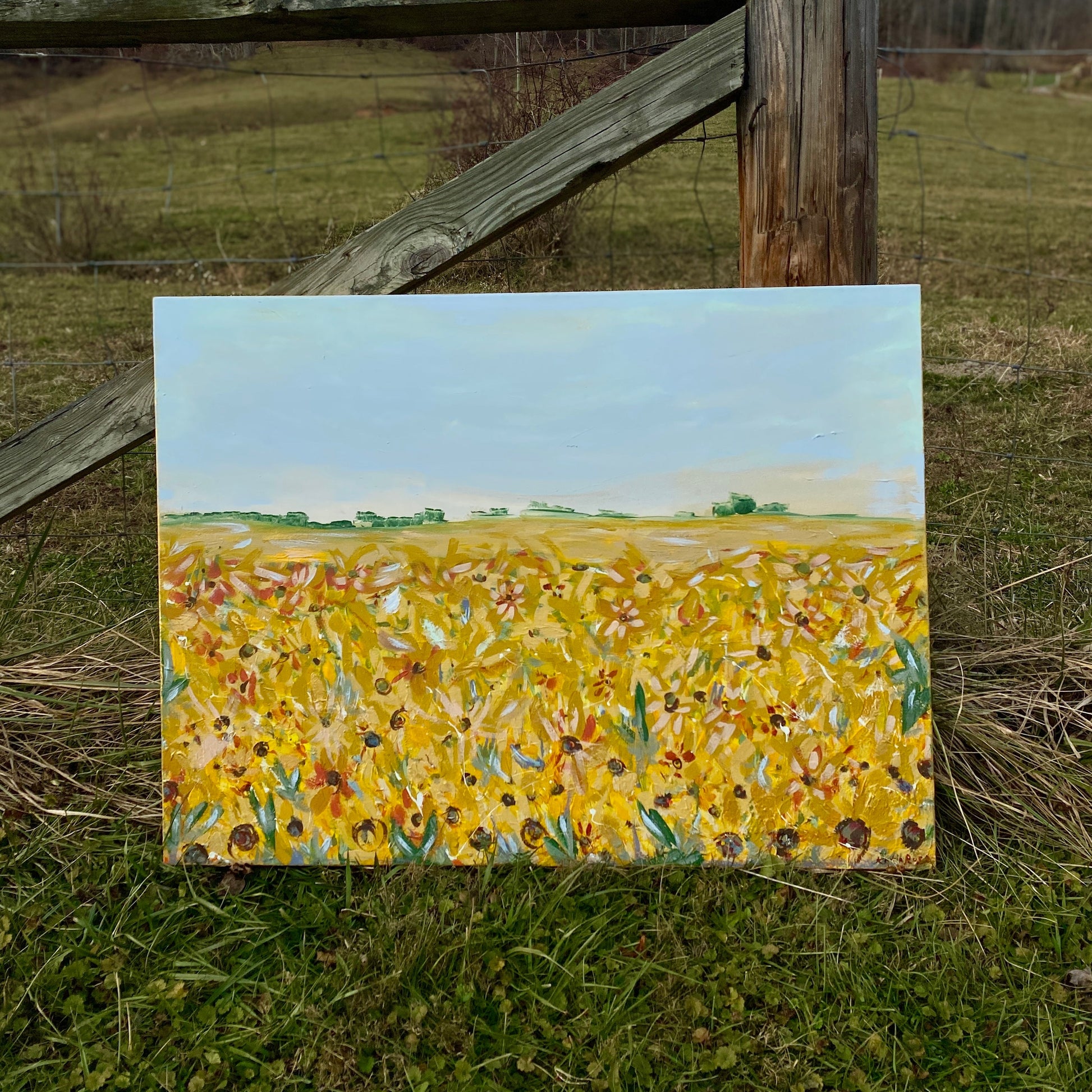 Painting of a sunflower field on a wooden easel outdoors.